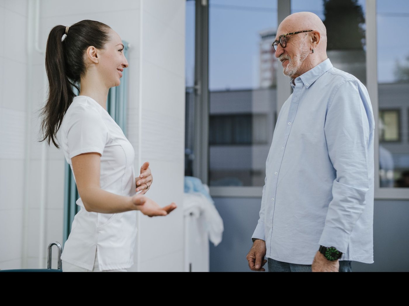 A clinician and an older patient share a smile at the end of a visit